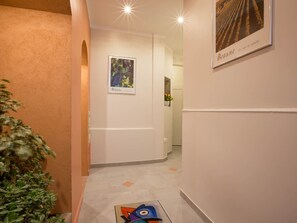 Un couloir orné d’un tableau encadré représentant des grappes de raisin, avec l’inscription « Beaune », et d’un autre tableau encadré représentant un vignoble.