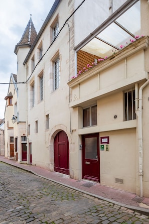 Ein historisches Gebäude mit roter Tür, einem Balkon mit Blumen und einer Kopfsteinpflasterstraße.