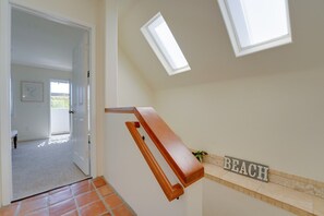 En gang med gelænder i træ, et skilt med 'BEACH' og en dør, der fører til et rum med udsigt over det åbne landskab.