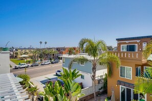 A residential area with modern houses, a street with parked cars, and palm trees.
