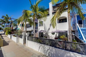 A residential area with houses, palm trees, and a gated entrance.