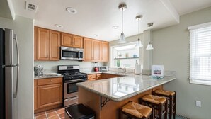 Una cocina moderna con armarios de madera, electrodomésticos de acero inoxidable y una isla grande con taburetes de bar.