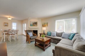 A living room with a sofa, armchair, dining table, and fireplace.