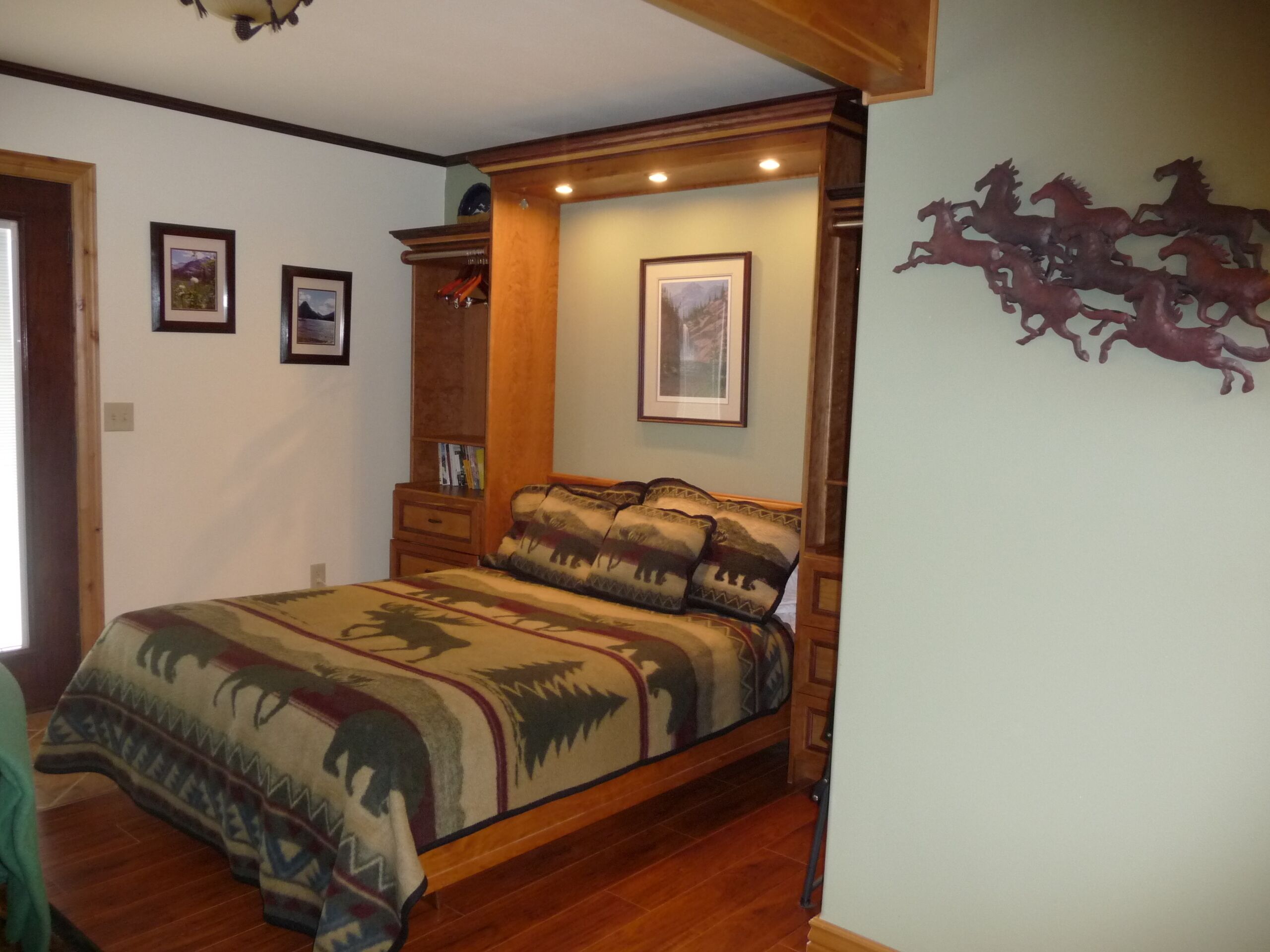 Une chambre à coucher avec un lit en bois, une table de chevet, une commode et une décoration murale représentant un cheval.