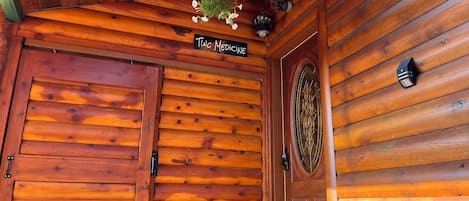 Una puerta de madera con un cartel arriba, una maceta colgante y un aplique de pared.
