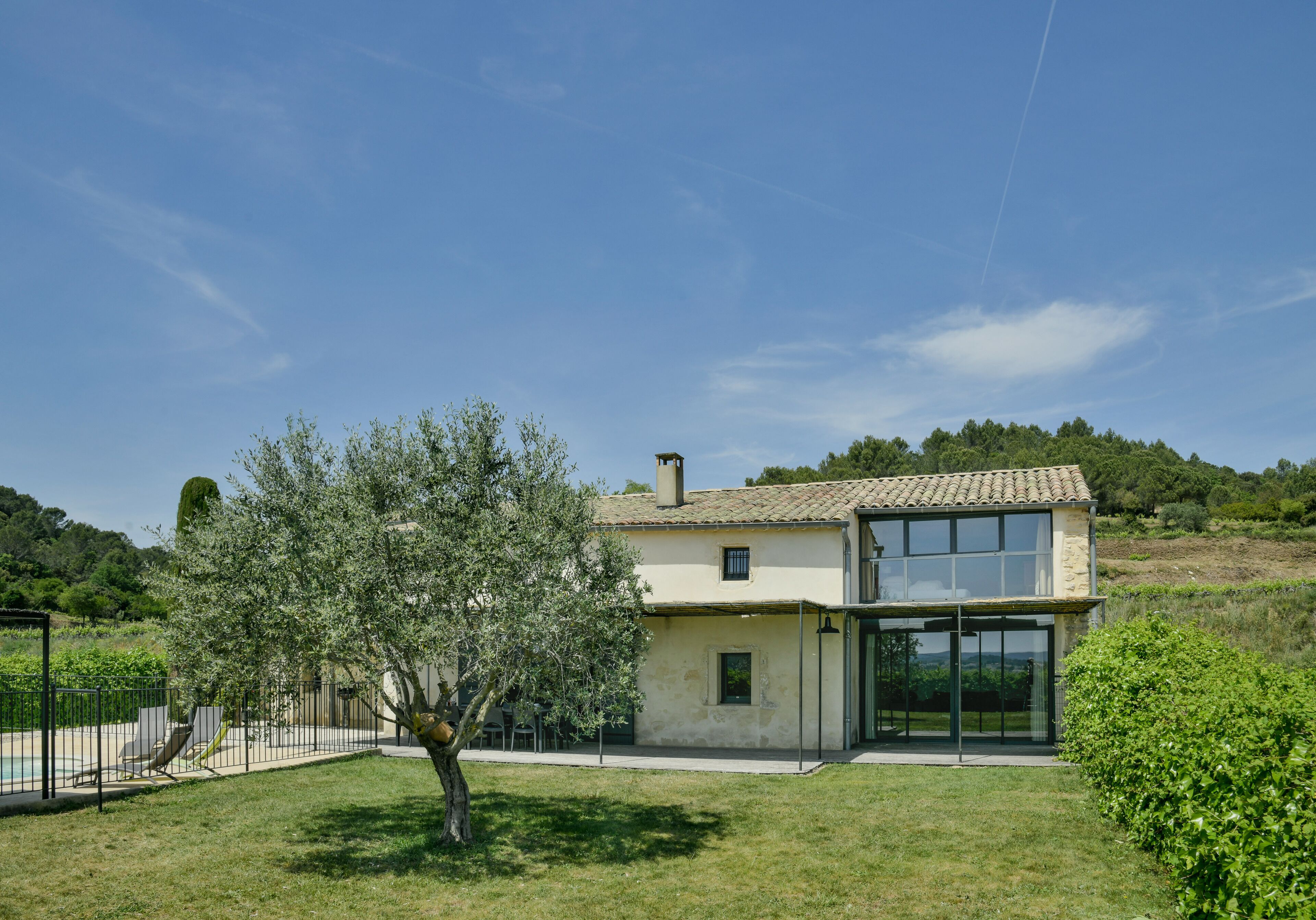 Une maison moderne dotée d’une grande porte vitrée, d’une piscine et d’un jardin bien entretenu.