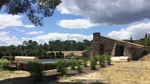 Un edificio de piedra rústico con piscina, rodeado de vegetación y árboles.