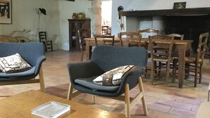 Una sala de estar con chimenea, muebles de madera y un sillón azul con cojín estampado.