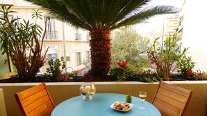 Une table ronde avec deux chaises en bois, un saladier en verre contenant du pain et un verre à vin posé sur une nappe bleue.