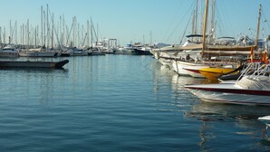Un port de plaisance où sont amarrés différents types de bateaux, avec une eau calme et un ciel dégagé.