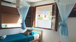 Une chambre avec deux lits, une fenêtre donnant sur un beau paysage et un luminaire suspendu.