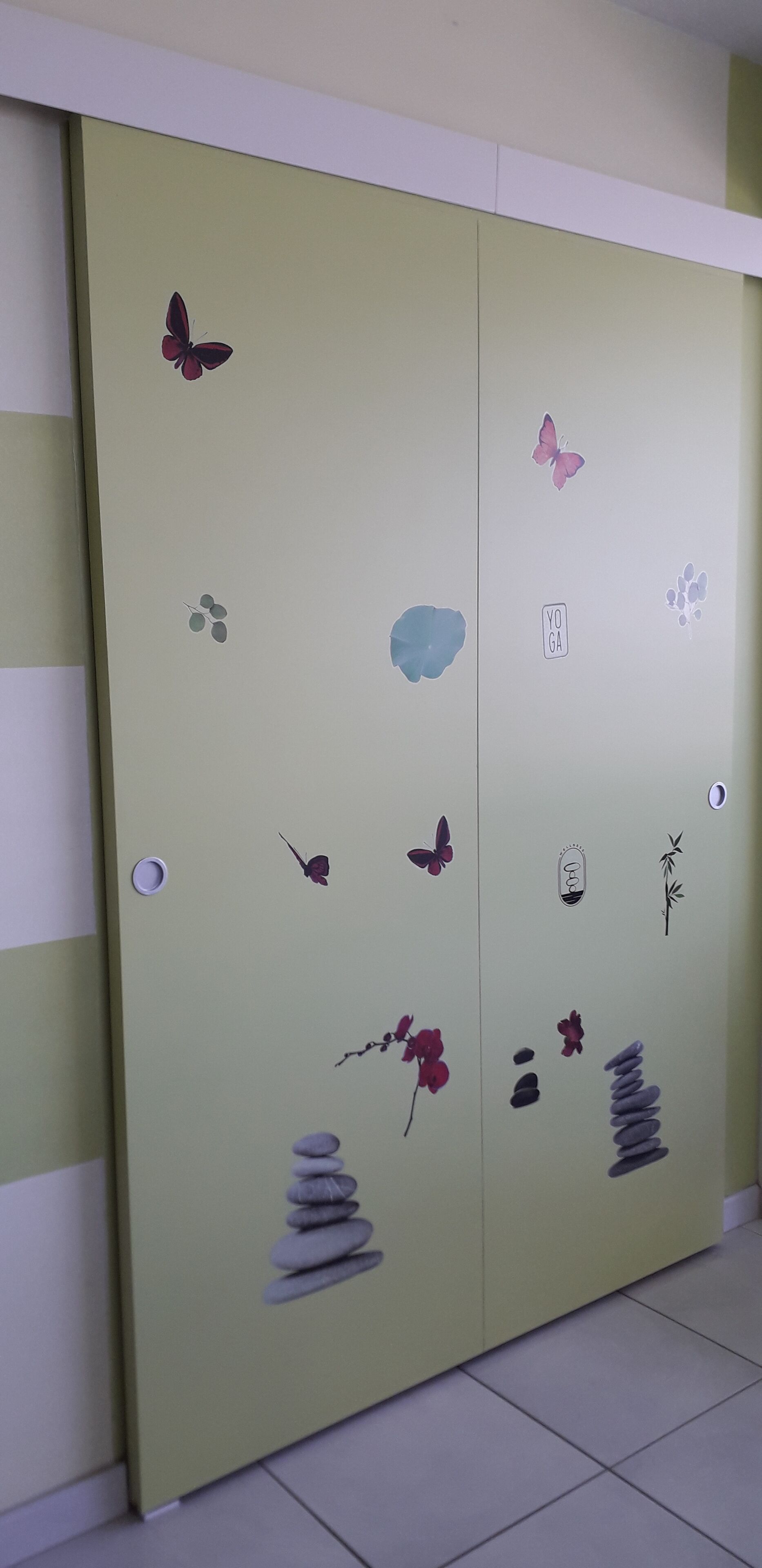Habitación con un armario verde decorado con adhesivos de mariposas y una pegatina que dice 'YOGA'.