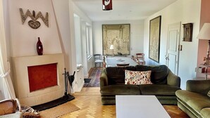 Ein Wohnzimmer mit Kamin, einer Couch, einem Couchtisch und einem Essbereich im Hintergrund.