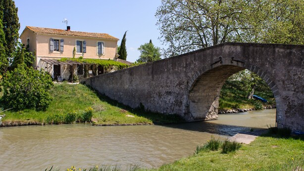 A stone bridge over a calm river, with a house in the background. - Private Courtyard and Pool, close to Carcassonne and Mediterranean Beaches (Argeliers)