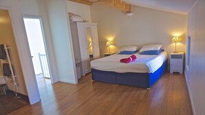 A bedroom with a bed, bedside lamps, a wardrobe, and a wooden floor. - Private Courtyard and Pool, close to Carcassonne and Mediterranean Beaches (Argeliers)