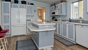 Une cuisine de taille réduite avec des meubles blancs, un îlot central et un four à micro-ondes.