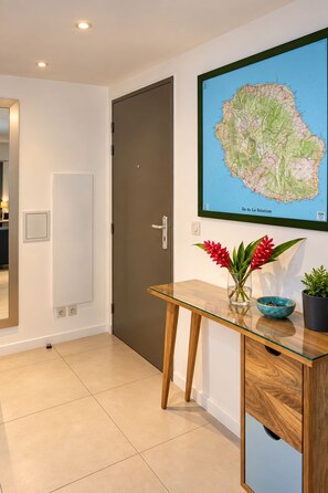 Un couloir avec une table en bois, une carte accrochée au mur et une porte.