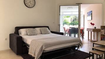 A modern bedroom with a bed, a clock, and a view of the outdoors.