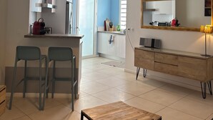 Una cucina moderna con pensili bianchi, una lampada a sospensione nera e un'isola con un bollitore.