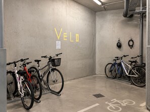 Un espace de stationnement pour vélos avec le mot « VÉLO » écrit sur le mur, un support à vélos et un casque suspendu au mur.