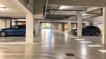 Een parkeergarage met meerdere verdiepingen, betonnen pilaren, een nette vloer en geparkeerde auto's.