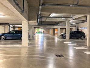 Un parking à plusieurs niveaux, avec des piliers en béton, un sol propre et des voitures garées.