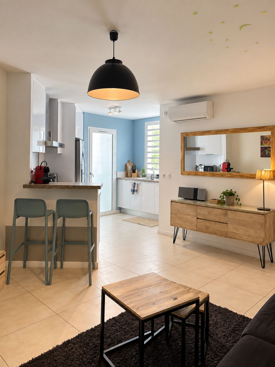 A modern kitchen with a dining area, a large mirror, and a black pendant light.