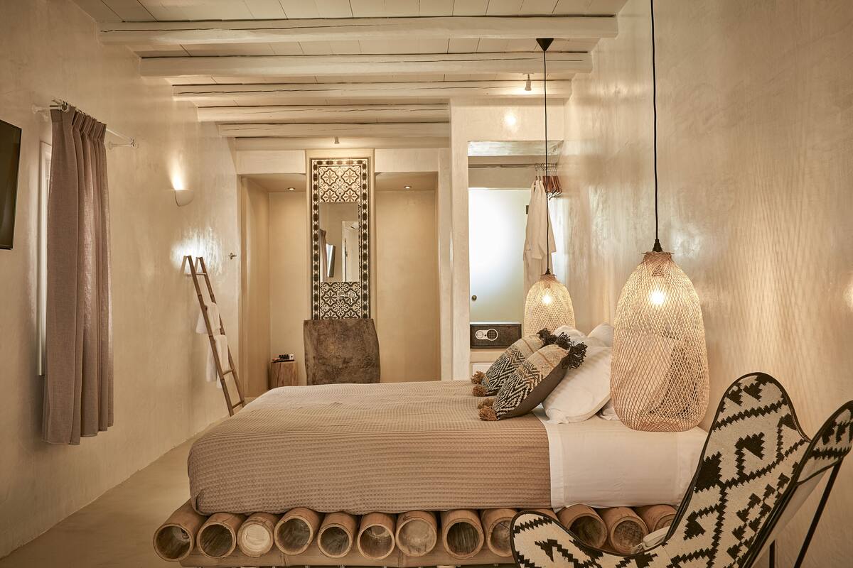 Une chambre à coucher comprenant un lit, un miroir, une armoire et un luminaire suspendu.