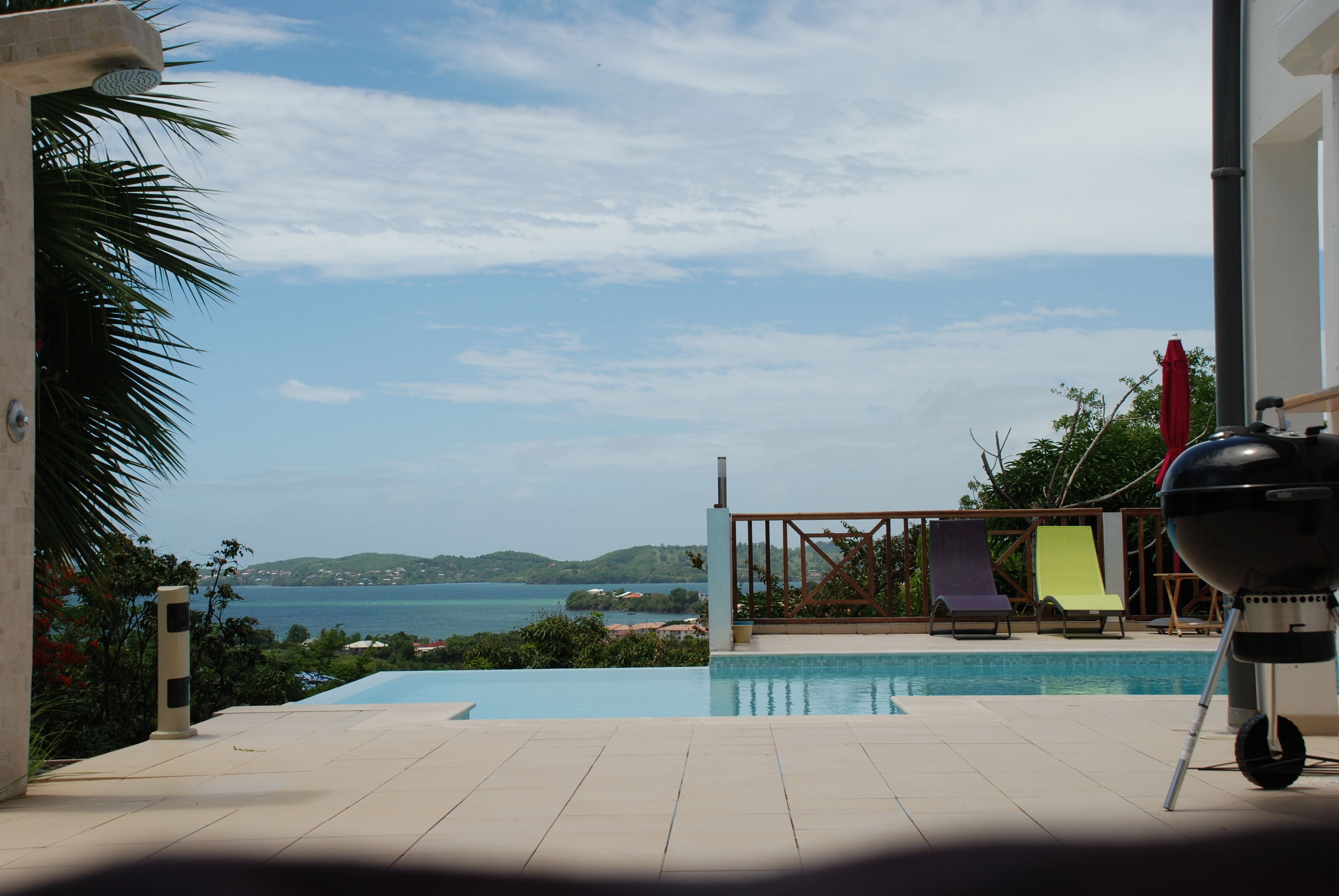 Una piscina con vista sul mare e sulle colline, un barbecue e lettini.