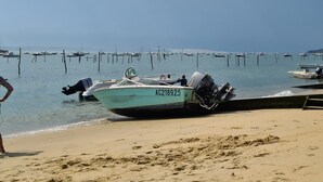 A beach with boats docked in the water and a sandy shore.