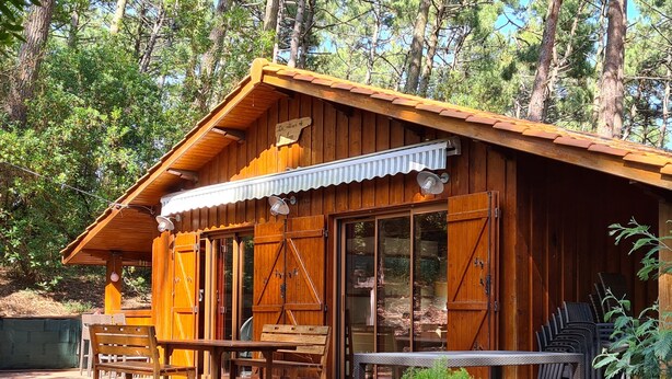 A wooden cabin with a covered patio, wooden furniture, and a small garden area.