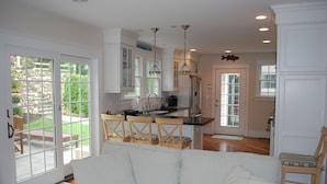 A modern kitchen with white cabinetry, a central island, and pendant lighting. - Experience Hy-View Hyannisport Exceptional Summer Getaway (Hyannisport)
