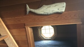 A wooden staircase leading to a loft bedroom with a skylight and a hanging fish decoration. - Experience Hy-View Hyannisport Exceptional Summer Getaway (Hyannisport)
