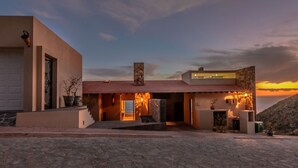 A modern house with a stone facade, a flat roof, and a view of the sunset.