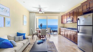 A spacious living room with a balcony, a dining area, and a kitchen with stainless steel appliances.