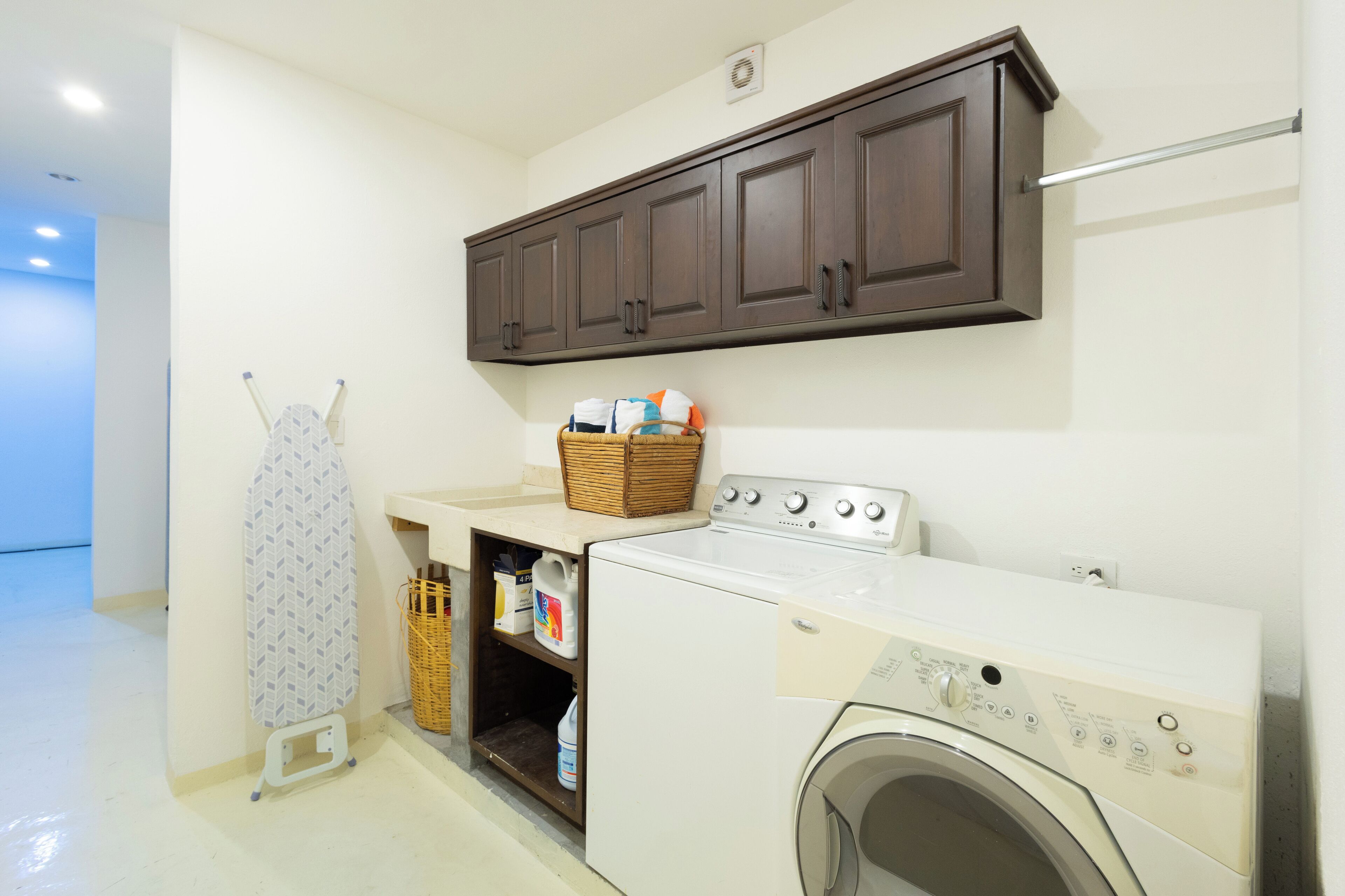 A laundry room with a washing machine, a dryer, a drying rack, and a cabinet above the dryer.