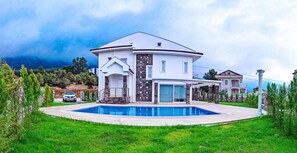 Una casa de dos pisos con piscina, garaje y césped bien cuidado.