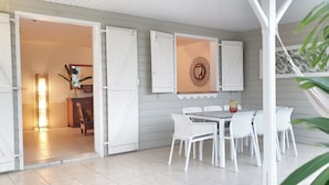 Een open terras met witte meubels, een eettafel en een hangmat.
