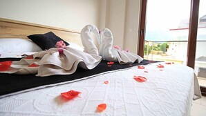 Habitación de hotel con una cama, almohada negra y toalla blanca dispuesta en forma de cisne.
