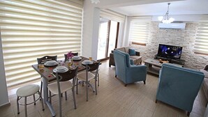 Una sala de estar moderna con comedor, televisor y pared de piedra.