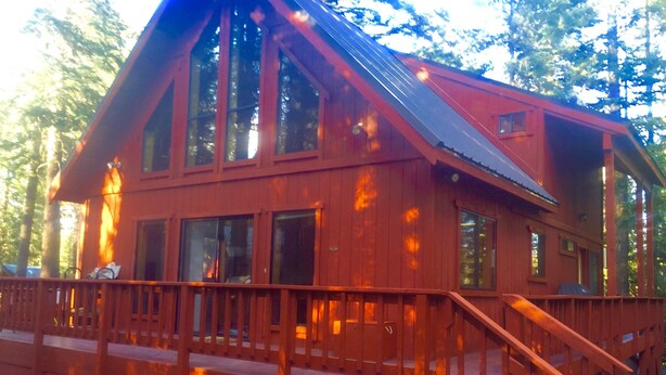 Une grande cabane en bois à deux étages, dotée d’un balcon et d’un escalier.