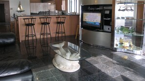 Eine moderne Küche mit Backofen, einem Esstisch mit Glasplatte und einer Bar mit Hockern.