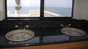 Ein Badezimmer mit zwei Waschbecken und einem großen Fenster mit Meerblick.