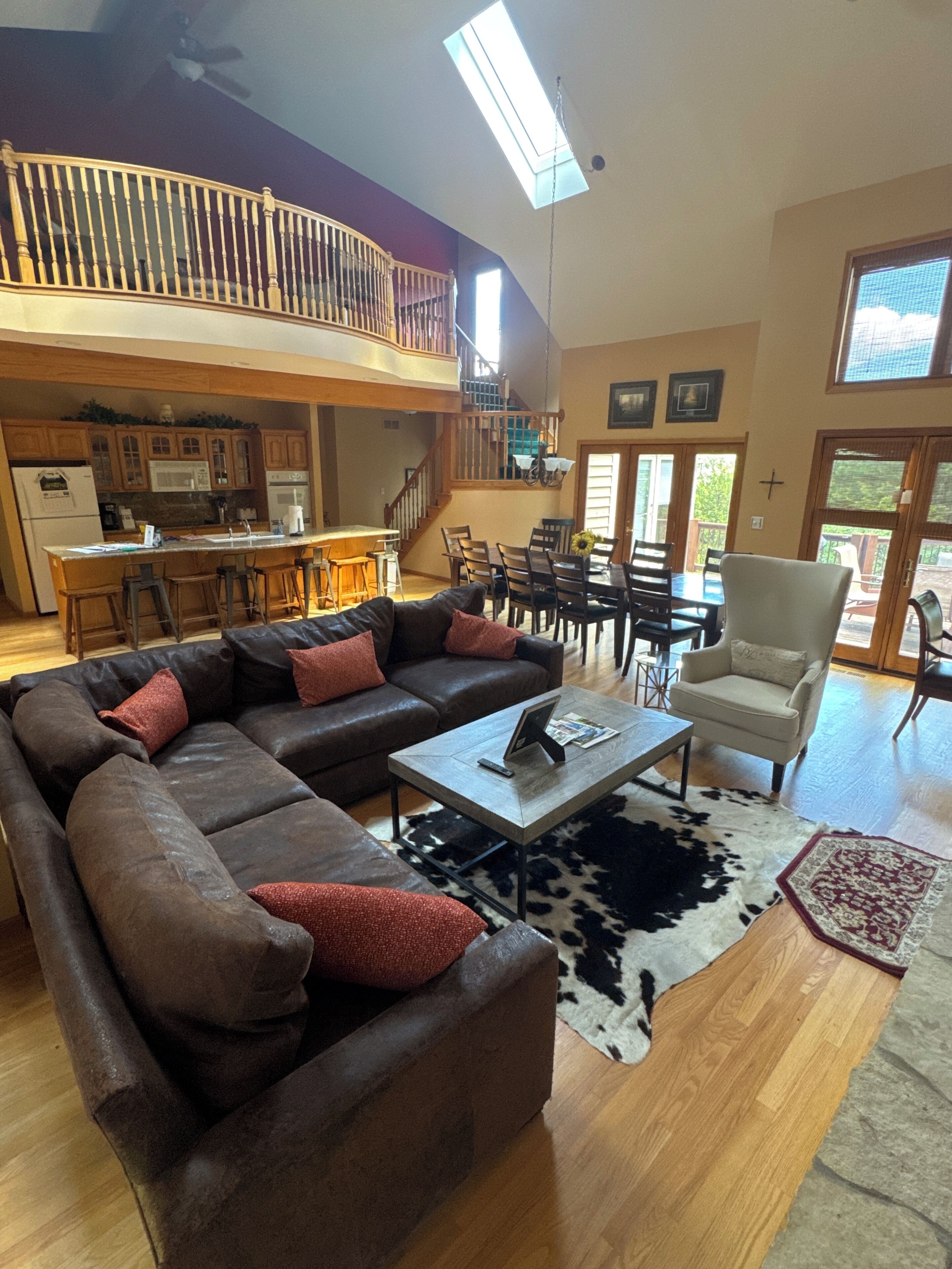 A spacious living area with a sectional sofa, a dining table, and a kitchen in the background.