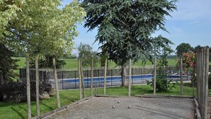 An outdoor area with a gravel surface, surrounded by a wooden fence and trees.