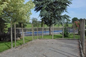 An outdoor area with a gravel surface, surrounded by a wooden fence and trees.