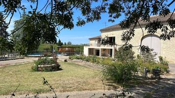 En fastighet med en stor, öppen gård, en swimmingpool och en byggnad med ett garage.