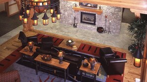 A cozy lounge area with a stone fireplace, multiple seating options including sofas and chairs, and ambient lighting from lantern-style fixtures.