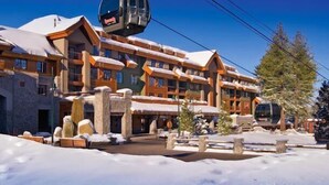A multi-story hotel with a ski lift, stone architecture, and snow-covered surroundings.
