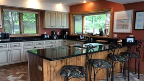 Una cocina con una isla grande, taburetes de bar, armarios de madera y un suelo con patrón de espiga.